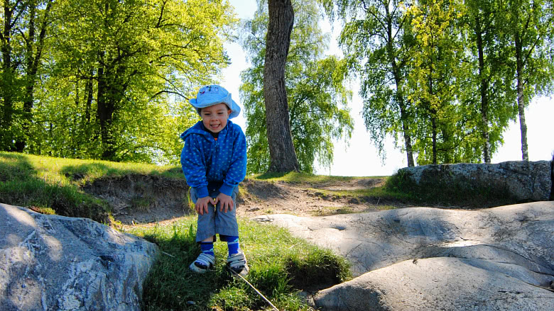 Pieni poika seisoo Ruissalon kalliolla ja nauraa
