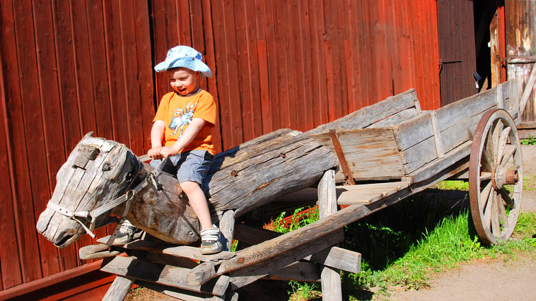 Pieni poika ratsastaa puuhevosella Kuralan kylämäessä