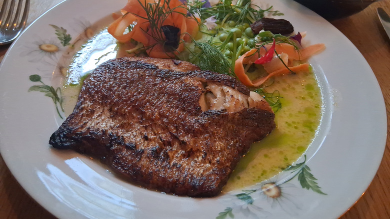 Paistettua siikaa ja vihreitä kasviksia koristeellisella lautasella